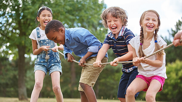 Tauziehende Kinder auf einer Wiese