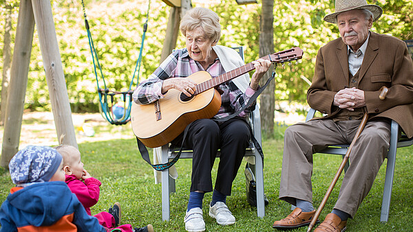 Seniorin spielt Kleinkindern auf der Gitarre vor