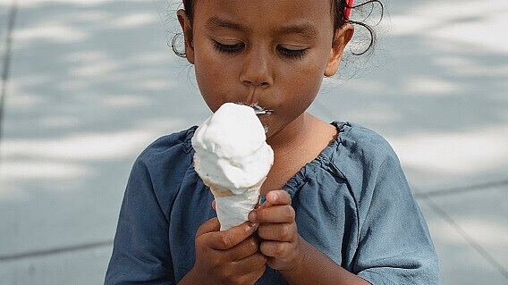 Kind isst ein großes Eis im Freien.