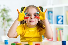 Mädchen in Kita beim Malen mit Fingerfarbe