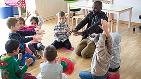Kindergartenkinder beim Spielen mit einem Betreuer