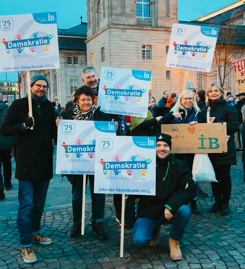 IB-Mitarbeitende halten Plakate bei der Demonstration für Demokratie und gegen Rechtsextremismus in Darmstadt