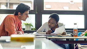 Mann und Frau sitzen an Unterrichtstischen