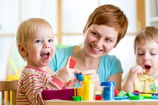 Zwei spielende Kinder zusammen mit einer Betreuerin