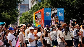 Menschen stehen vor einem bunt geschmückten CSD-Truck des IB