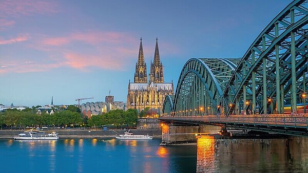 Blick auf den Kölner Dom und die Hohenzollernbrücke über den Rhein bei Abenddämmerung