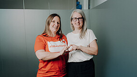 Zwei Frauen zeigen mit den Händen ein Herz