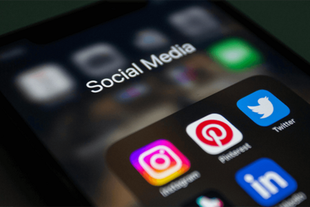 Nahaufnahme eines Smartphone-Bildschirms mit dem Ordner 'Social Media' und den App-Symbolen von Instagram, Pinterest, Twitter und LinkedIn