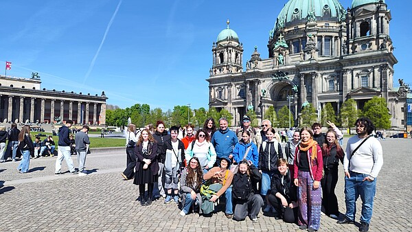 Gruppenporträt der Teilnehmenden des IB-Jugendaustauschs aus Deutschland und Frankreich auf einem Platz in Berlin, im Hintergrund ein historisches Gebäude.