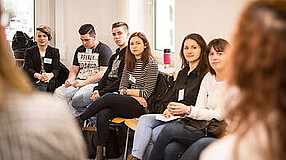 Gruppe von Jugendlichen sitzen auf Stühlen