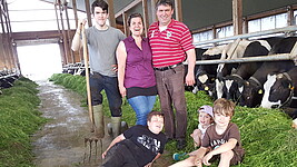Eine Familie im Stall neben Kühen