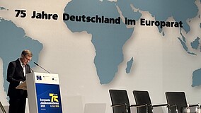 Ein Redner spricht am Pult, im Hintergrund ist eine Europakarte mit dem Konferenztitel zu sehen