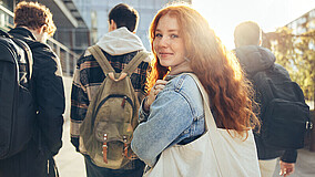 Symbolbild: Jugendliche auf dem Schulhof, ein Mädchen blickt zurück, während drei Jungen nach vorne gehen – steht für das vorzeitige Ende des Mental Health Coaches-Programms und die damit verbundene Unsicherheit bei Schülerinnen und Schülern.