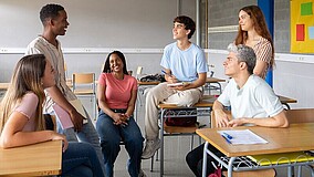 Fünf Jugendliche befinden sich in einem Klassenzimmer.