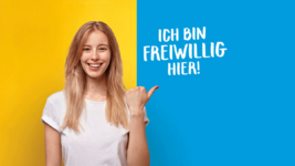 Junge Frau vor einem gelb-blauen Hintergrund. Auf dem blauen Hintergrund steht "Ich bin freiwillig hier!