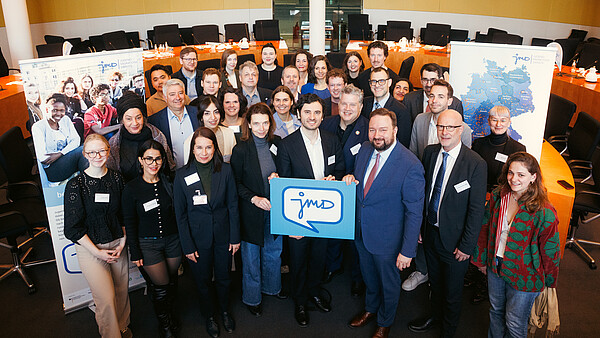 Gastgeber*innen und Teilnehmende des Parlamentarischen Frühstücks der Jugendmigrationsdienste im Deutschen Bundestag versammeln sich zum Gruppenfoto.