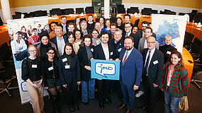 Gastgeber*innen und Teilnehmende des Parlamentarischen Frühstücks der Jugendmigrationsdienste im Deutschen Bundestag versammeln sich zum Gruppenfoto.