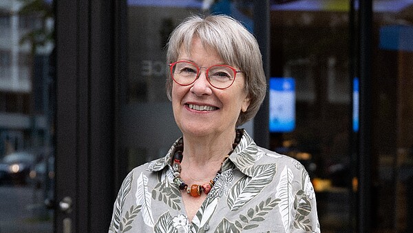 Petra Merkel lächelt ins Bild, trägt eine rote Brille