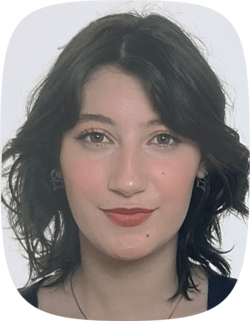 Porträt von Lotta Block: Eine junge Frau mit schulterlangem, gewelltem dunklem Haar, dezentem Make-up und silbernen Ohrringen in Form von Sternen.