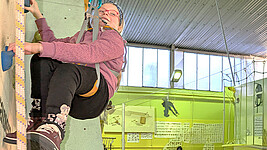 Ein Mädchen hängt gut gesichert an der Kletterwand.