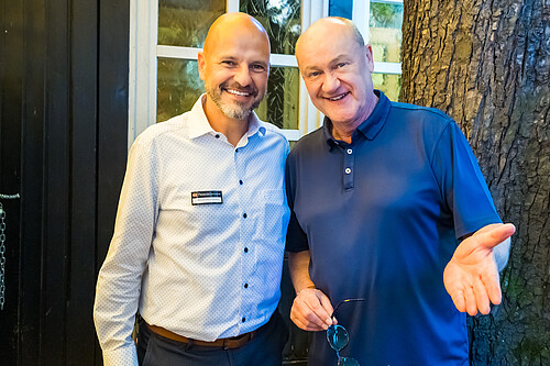 Zwei M&auml;nner l&auml;cheln in die Kamera.