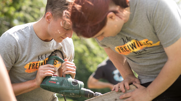 Zwei Freiwilligendienstleistende arbeiten mit Holz.