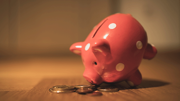 Sparschwein zusammen mit Münzen auf einem Tisch