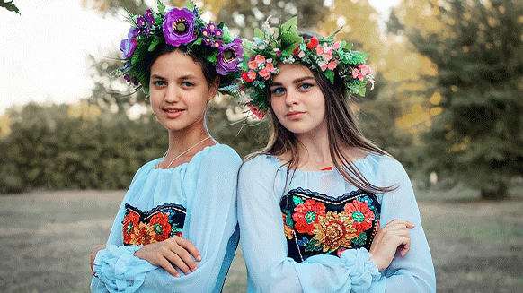 Zwei junge Mädchen mit ukrainischer Tracht und Blumenkränzen im Haar. 